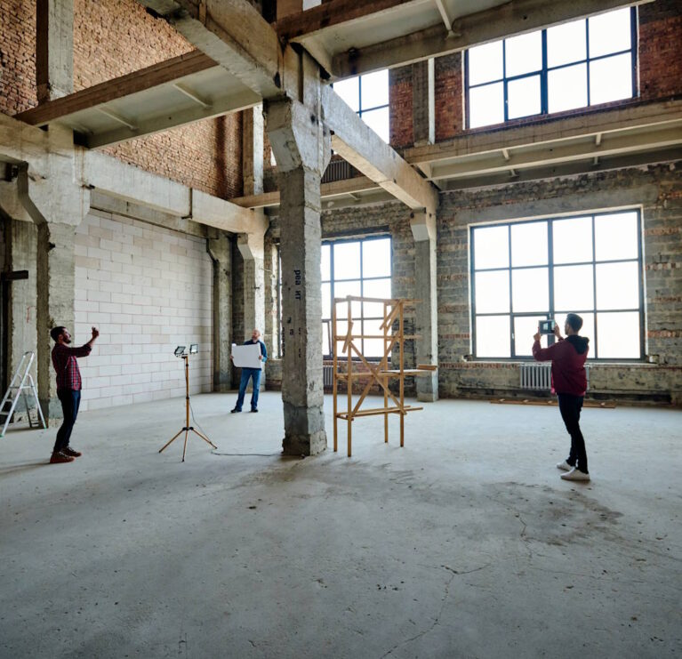 Two young contractors photographing unfinished structure inside building while their colleague looking at sketch on blueprint SSUCv3H4sIAAAAAAAACoxUyY7UMBC9I/EPLZ+x8Brbc+TADYk74lBeMm1NOm4lDjAazb/jJO1uNxoQN/tV1avFr/zy/t3hgCzM0aGHw8t6K/c4DMucJ8gxjQUmHy74FEYfphYJPuY0RRha0EJ2xxFOoYDjMgwr/LoZ0ZwhL3OYm2Tzcck5THNO7qnAvLKc468MBaAVoIxP/Qo0fA5yeCwF3DHWdr7t90M1bMYSUUzoa0jnIaAL917IYlfLlzCiiu5Z/kLxKcCSnz9+hvm4zuktqji7MAwwhrTMN9L98L32BY9hdM+3+ldogNNz20HBBFhFiVZYiY5j4SFgoAJw0JppqyUQCtcclXzl8smGOt2WkBIpu7ci/BTgNOe4PWAbYchdl7Qjb4X/8aD3Ke8IGLvF74fX5m2nMATYtXLhQMIKS1josbBgsZDEYC07jYmgjjPXc9m5mgFpSi1w4nGnWRkY6zw2lgLmXWAAVAem4OpsAiivOoW9lRQL5Xlx1h6zHjzpubdA+NW5M6EYncSWmVKG8QJrIAoDeK40c9ppv3W2TwU9/SzzOG0SvfQGi4+pkeyP5GBYHXgzgPMUXRwfm7CUj9v+1TCXljFPq1LQtbghpTPYou2HQ184Q8WPMM/F3Ve83aKy7enU5BlT3uZ+YUW+rNl6pZxxLYThjJShSs4oavf6GAvPVk4tcDkPCXzwd+r+QyBUGm66jkl509B1+WWxKWqYvtmu/8BmE4qri3Zqp2X7TrFk+I+smpjtO7lX3uYT/T9+KURVZ0phUqjtoS+BcU2JVFkMrTrAzgHDgtgeg9QCUyWCk2CtcbxEvf4GAAD//wMAXRv/D30FAAA=